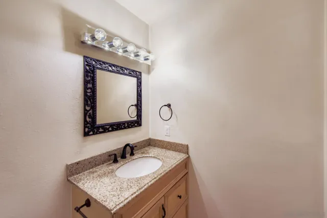 a bathroom with a granite countertop sink and a mirror