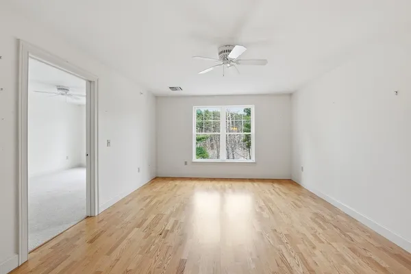 a view of an empty room with wooden floor and a window