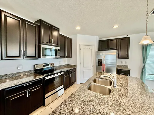 a kitchen with stainless steel appliances granite countertop a sink stove and refrigerator