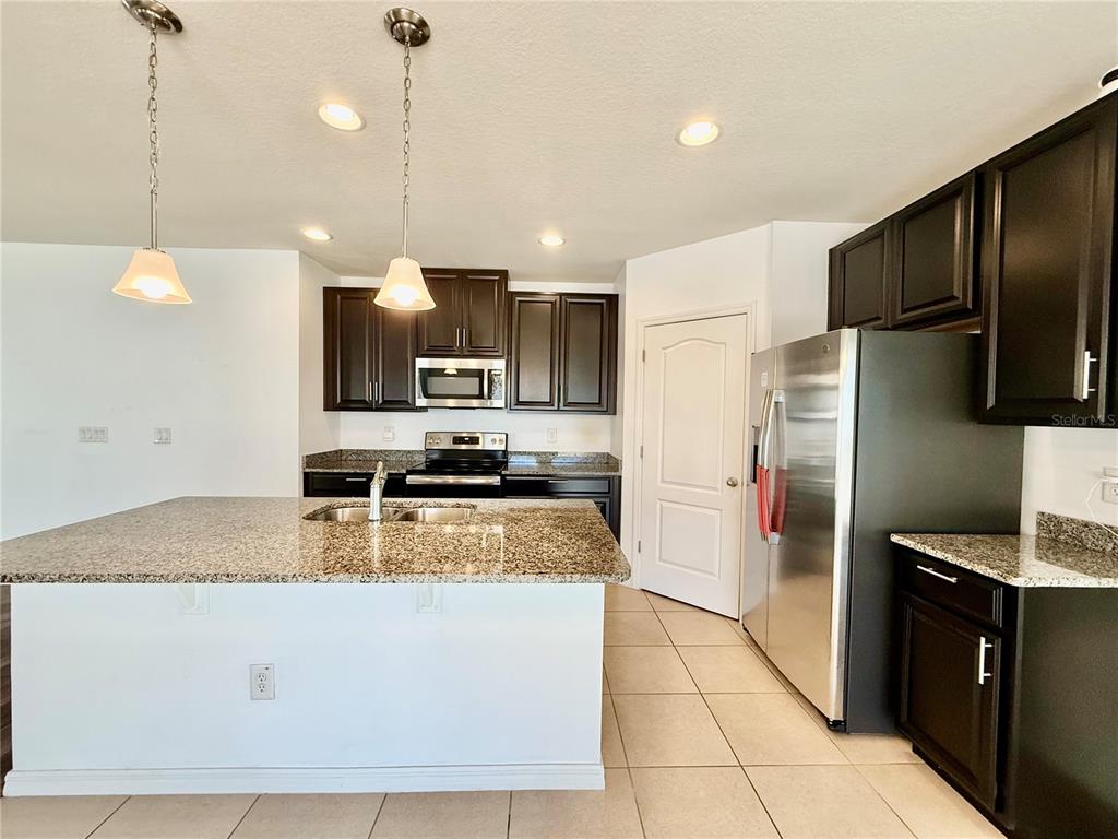 14207 Poke Ridge Drive Riverview, FL 33579 - Photo 9 of 34 a kitchen with stainless steel appliances granite countertop a refrigerator a sink a stove a microwave and island