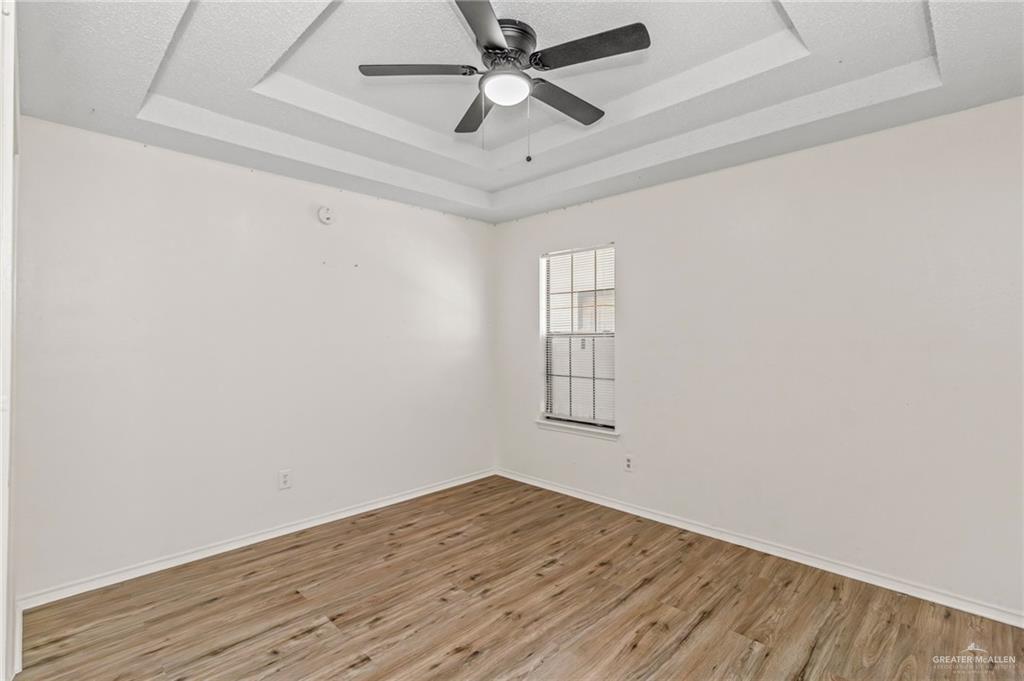 4601 South 24th Street, Unit 3 McAllen, TX 78503 - Photo 6 of 9 Unfurnished room with a raised ceiling, wood finished floors, and a ceiling fan