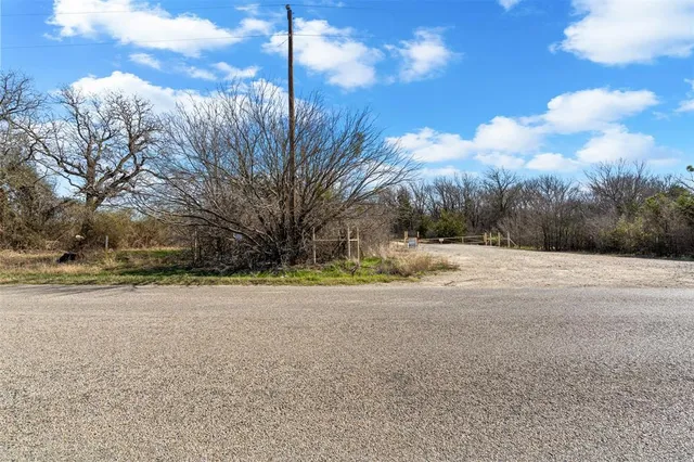 a view of dirt field with trees in the background