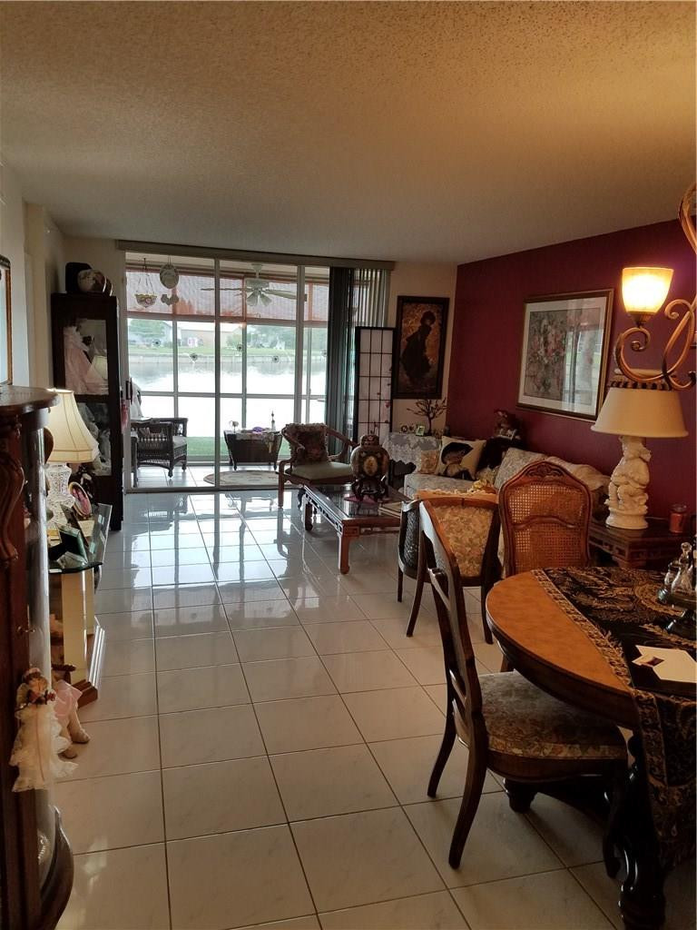 9587 Weldon Circle, Unit 110 Tamarac, FL 33321 - Photo 6 of 7 a living room with furniture a large window and a fireplace