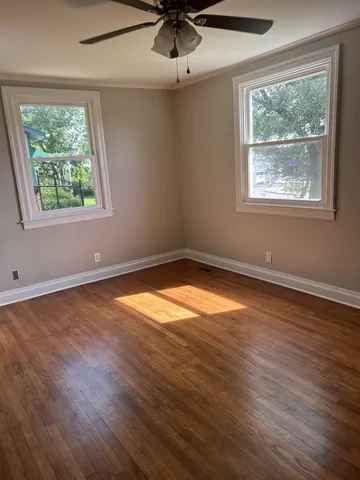 an empty room with wooden floor and windows