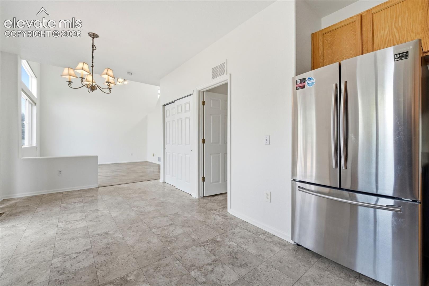 7904 Coffee Road Peyton, CO 80831 - Photo 10 of 48 Kitchen area featuring tile flooring, stainless steel refrigerator, and wood-finish cabinetry