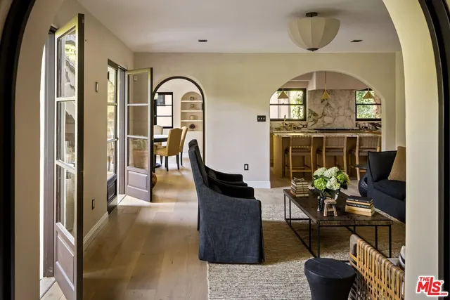 a living room with couches chairs and potted plant next to a window