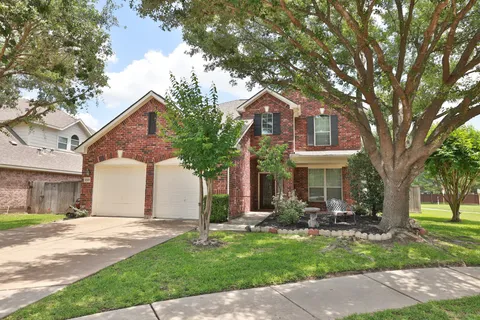 a front view of a house with garden and trees