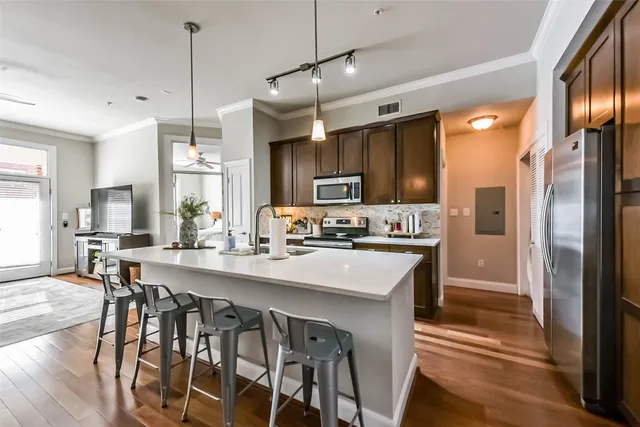 a kitchen with stainless steel appliances granite countertop a refrigerator a stove top oven a sink dishwasher and white cabinets with wooden floor