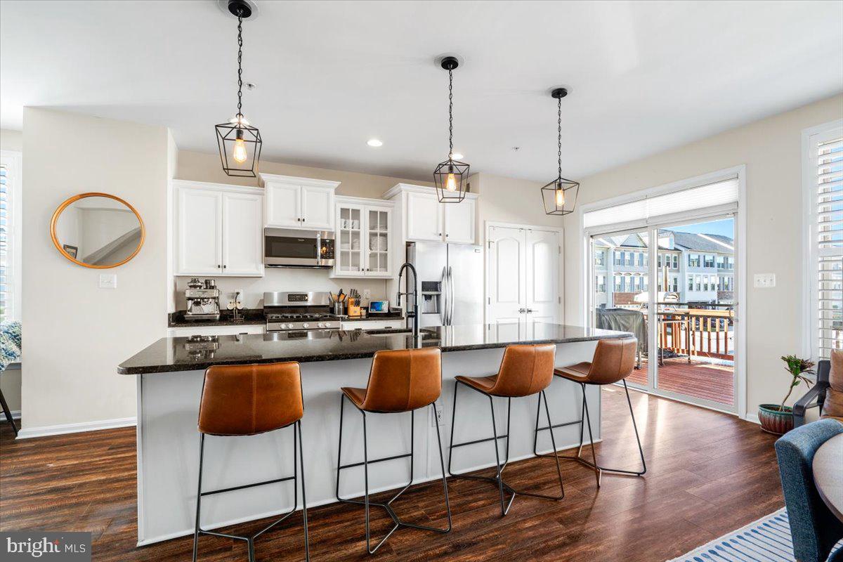 6500 Newton Drive Frederick, MD 21703 - Photo 4 of 36 a kitchen with stainless steel appliances granite countertop a stove a sink a dining table and chairs with wooden floor