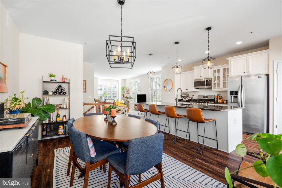 6500 Newton Drive Frederick, MD 21703 - Photo 6 of 36 a kitchen with stainless steel appliances granite countertop a stove a sink dishwasher a refrigerator a dining table and chairs with wooden floor