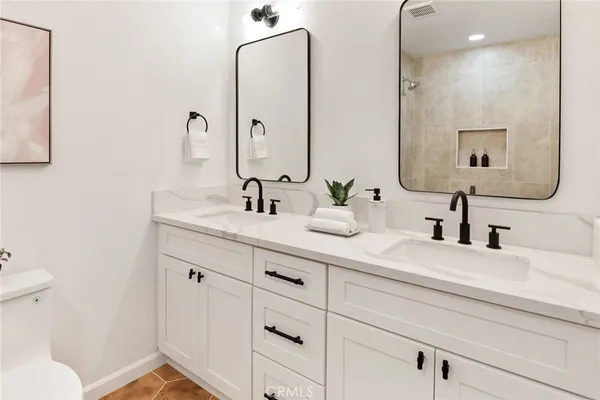 a bathroom with double vanity sink a mirror and a toilet
