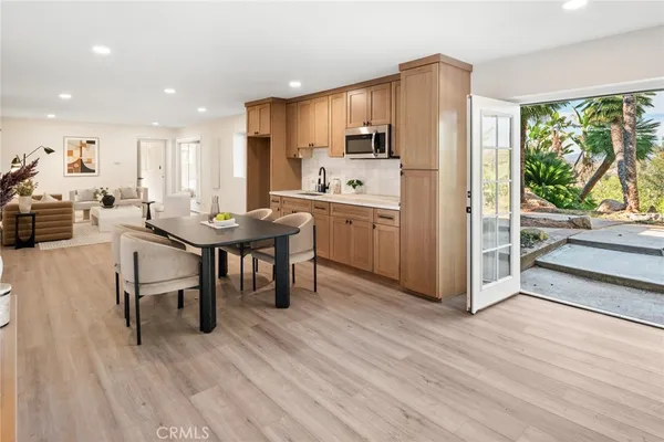 a kitchen with stainless steel appliances kitchen island granite countertop a table chairs sink and cabinets