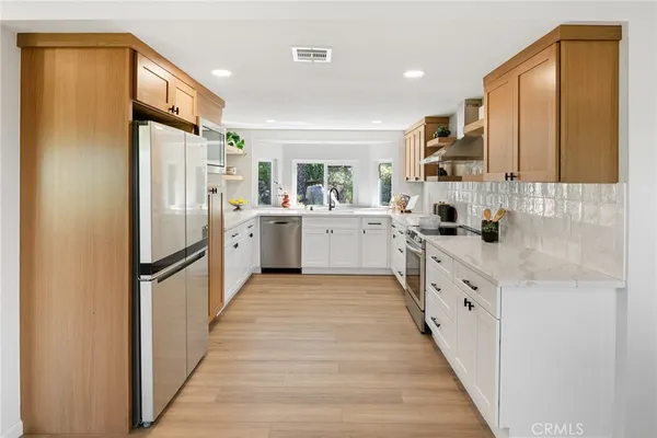 a kitchen with white cabinets and stainless steel appliances