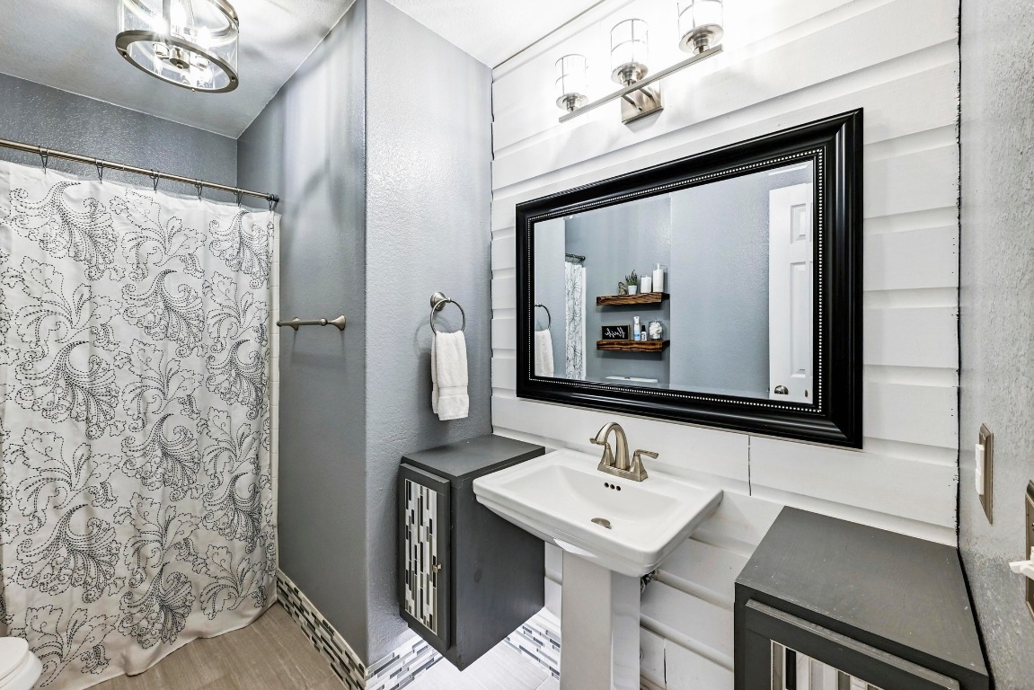 280 Spruce Drive Kyle, TX 78640 - Photo 21 of 30 Full bathroom featuring a shower with shower curtain, a textured wall, and light wood finished floors
