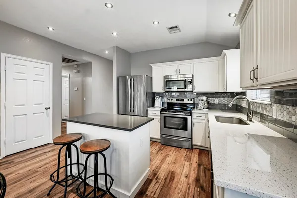 a kitchen with a sink stove cabinets and wooden floor