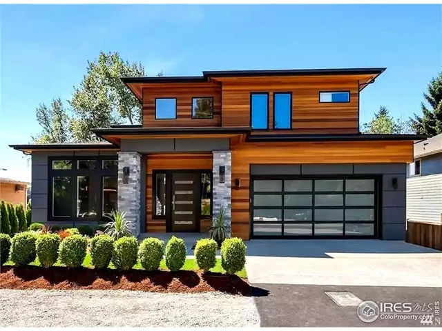 a front view of a house with a large window and potted plants