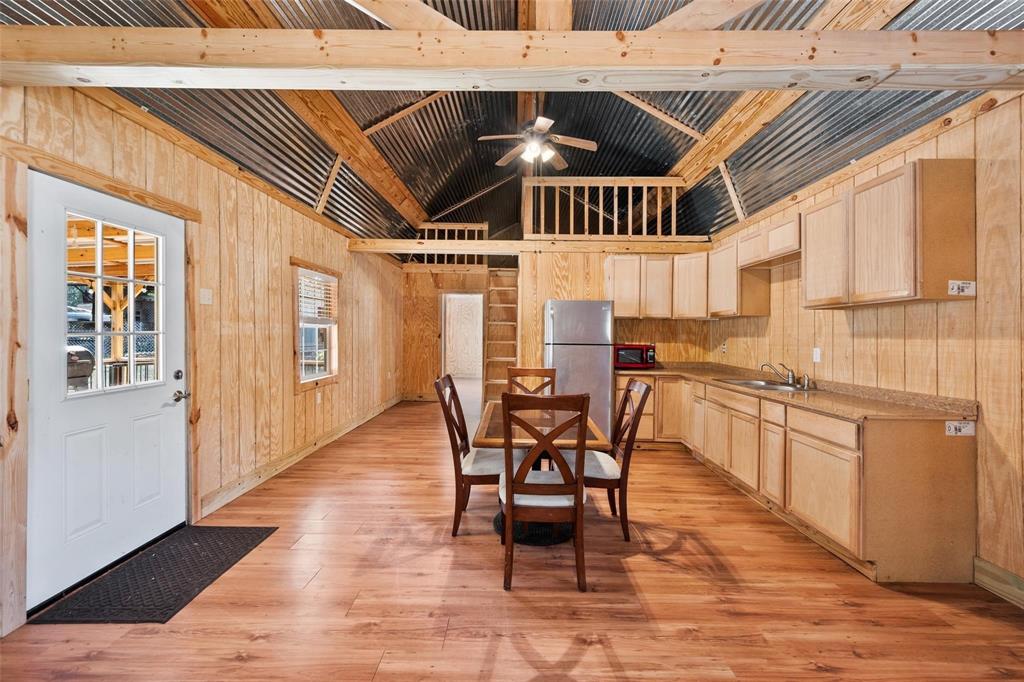 134 Maple Avenue Streetman, TX 75859 - Photo 15 of 19 Kitchen featuring light brown cabinets, wooden walls, freestanding refrigerator, light wood finished floors, and high vaulted ceiling