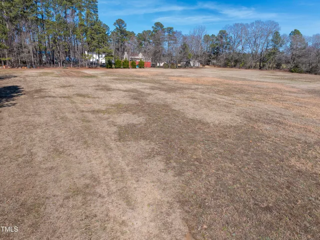a view of dirt field with trees in the background