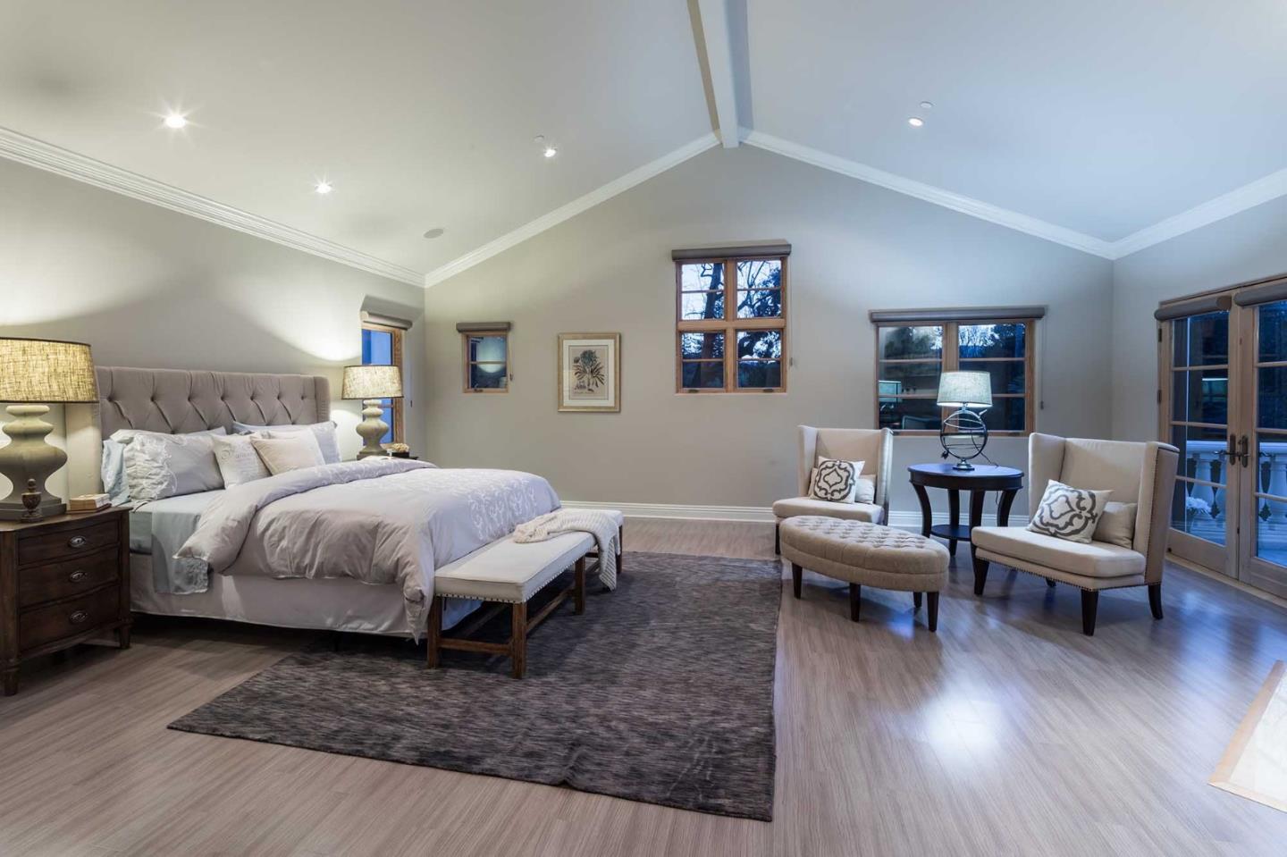 84 Nora Way Atherton, CA 94027 - Photo 27 of 37 a spacious bedroom with a bed a couch and a bookshelf with wooden floor