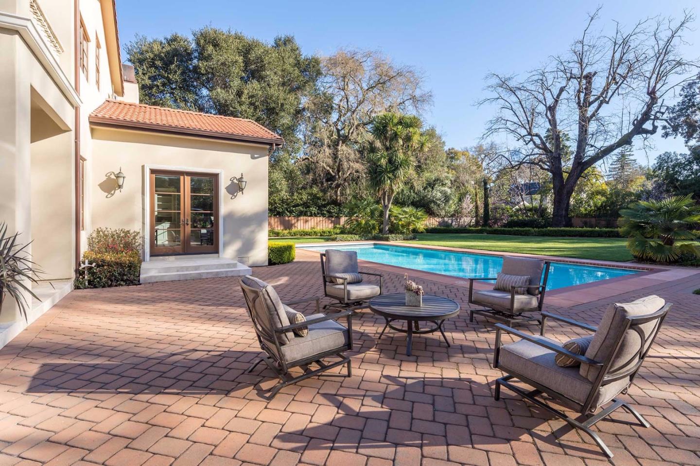 84 Nora Way Atherton, CA 94027 - Photo 31 of 37 a view of a patio with table and chairs under an umbrella with large trees