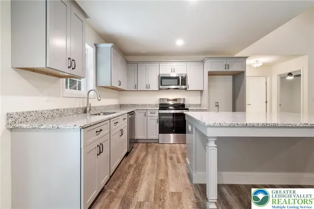 a kitchen with kitchen island granite countertop a sink a counter top space stainless steel appliances and cabinets