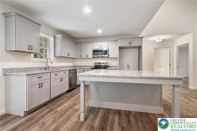 a kitchen with kitchen island granite countertop a sink cabinets and stainless steel appliances
