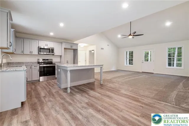 a open kitchen with kitchen island a stove a sink dishwasher and a refrigerator with wooden floor