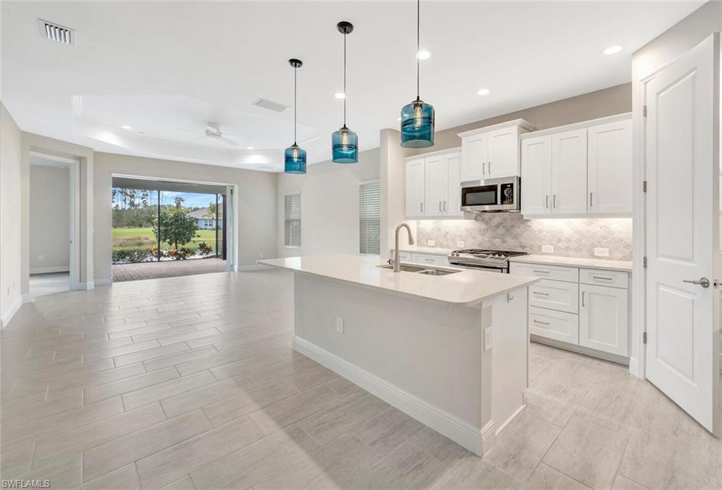 2247 Marquesa Circle Naples, FL 34112 - Photo 3 of 27 a kitchen with kitchen island white cabinets and refrigerator