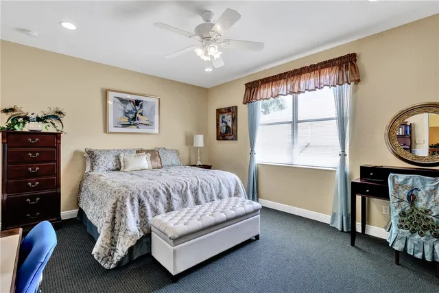 a spacious bedroom with a bed a dresser and paintings on the wall