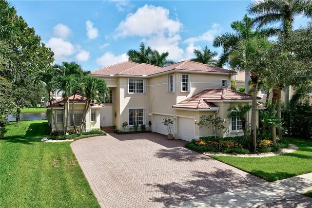 a view of a white house with a yard plants and large tree
