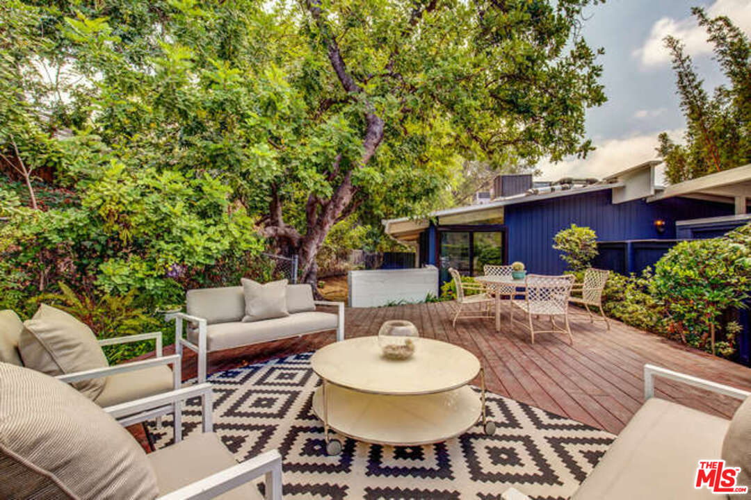 810 Bramble Way Los Angeles, CA 90049 - Photo 12 of 32 a view of a patio with couches table and chairs under an umbrella with large trees