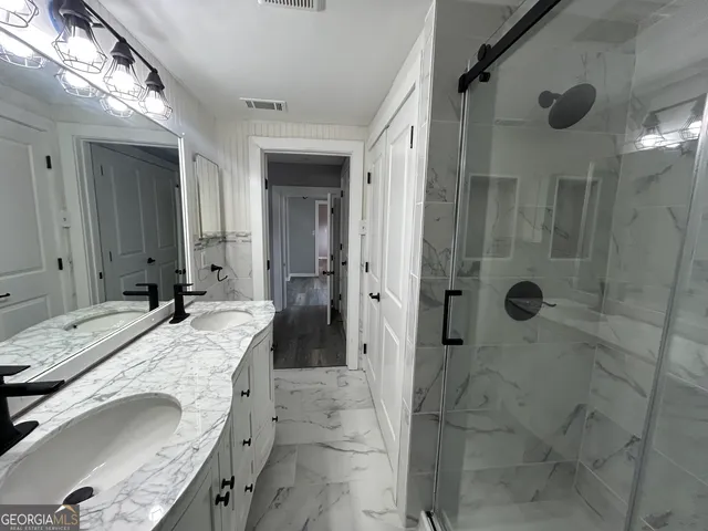 a bathroom with a granite countertop sink a mirror and shower