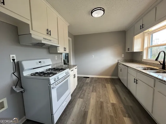 a kitchen with granite countertop a sink a stove and cabinets