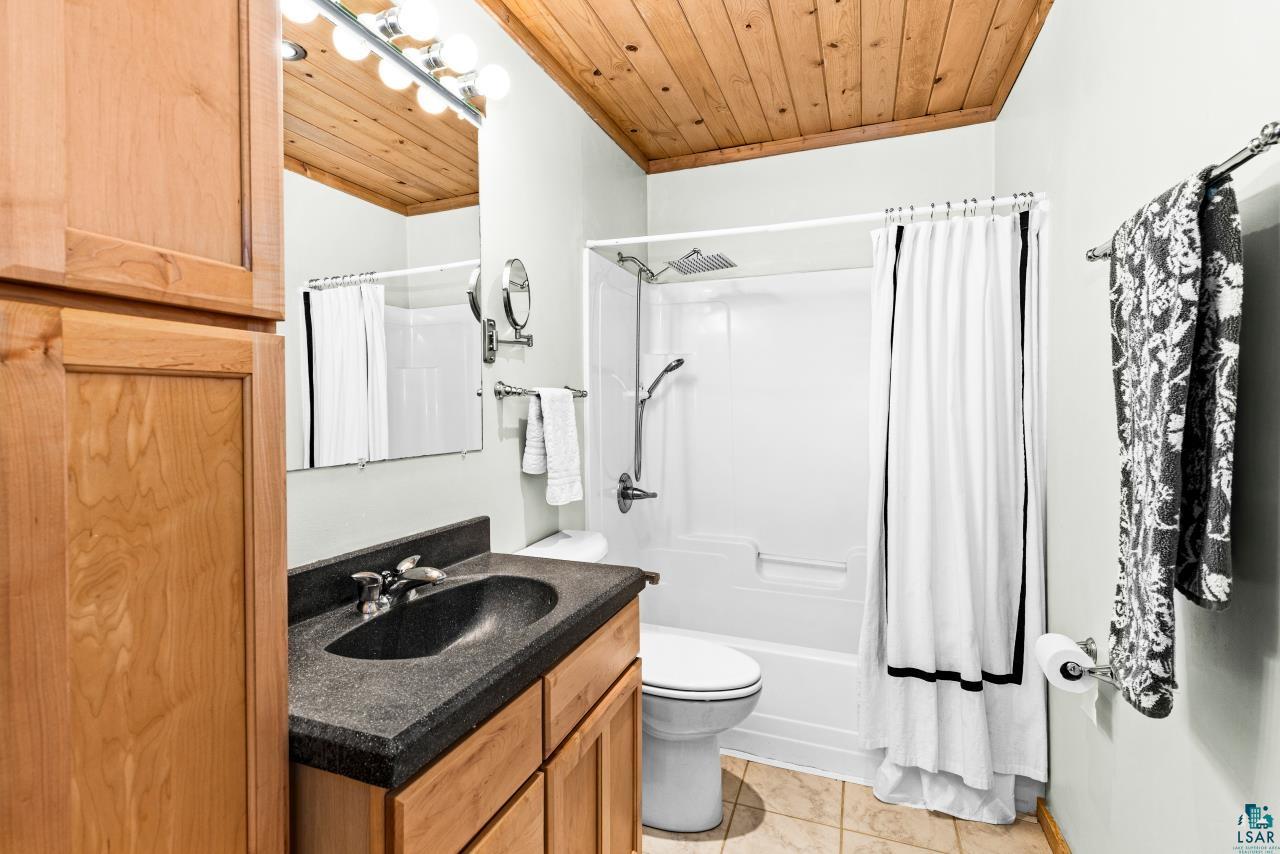 67 Snowshoe Trail Tofte, MN 55615 - Photo 9 of 42 Full bath with wooden ceiling, vanity, shower / bath combo with shower curtain, and light tile patterned floors