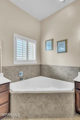 a bathroom with a granite countertop tub a sink and a window