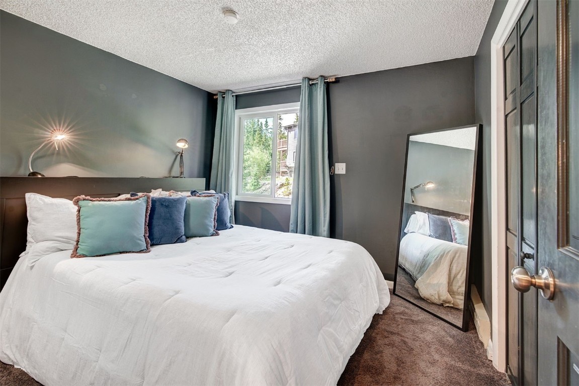 73 Illinois Gulch Road, Unit 8 Breckenridge, CO 80424 - Photo 14 of 24 a bedroom with a large bed and a chandelier