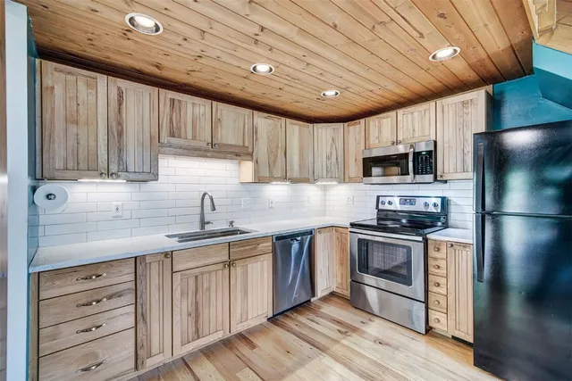 a kitchen with stainless steel appliances granite countertop wooden cabinets a sink a stove a refrigerator and cabinets