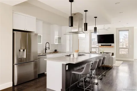 a kitchen with stainless steel appliances a stove top oven a refrigerator a sink a dining table and chairs with wooden floor