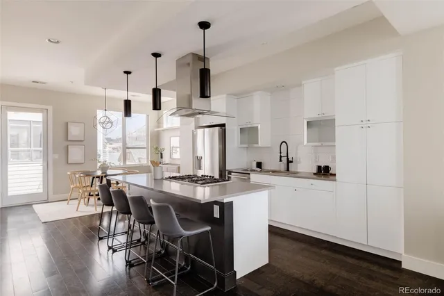 a kitchen with stainless steel appliances a dining table chairs and white cabinets