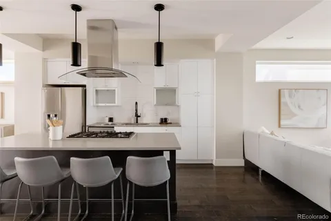 a kitchen with stainless steel appliances a dining table chairs and white cabinets