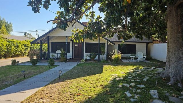 a view of a patio with table and chairs potted plants and large tree