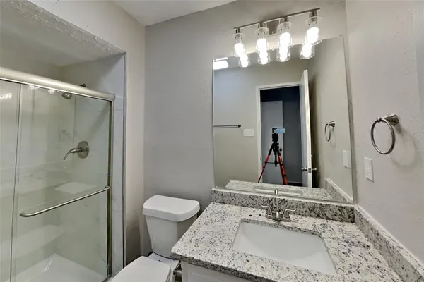 a en suite bathroom with a granite countertop sink a toilet and shower