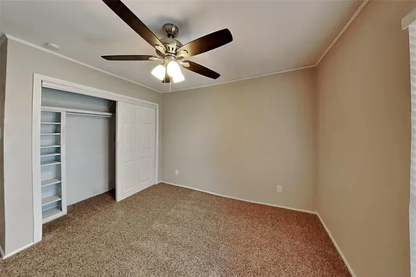an empty room with closet and a chandelier fan