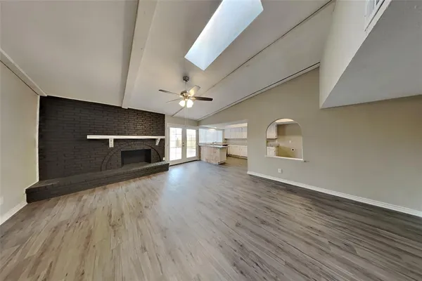 an empty room with wooden floor fireplace and windows