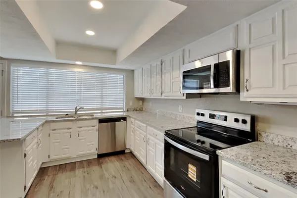 a kitchen with stainless steel appliances granite countertop grey cabinets a stove a sink and a microwave