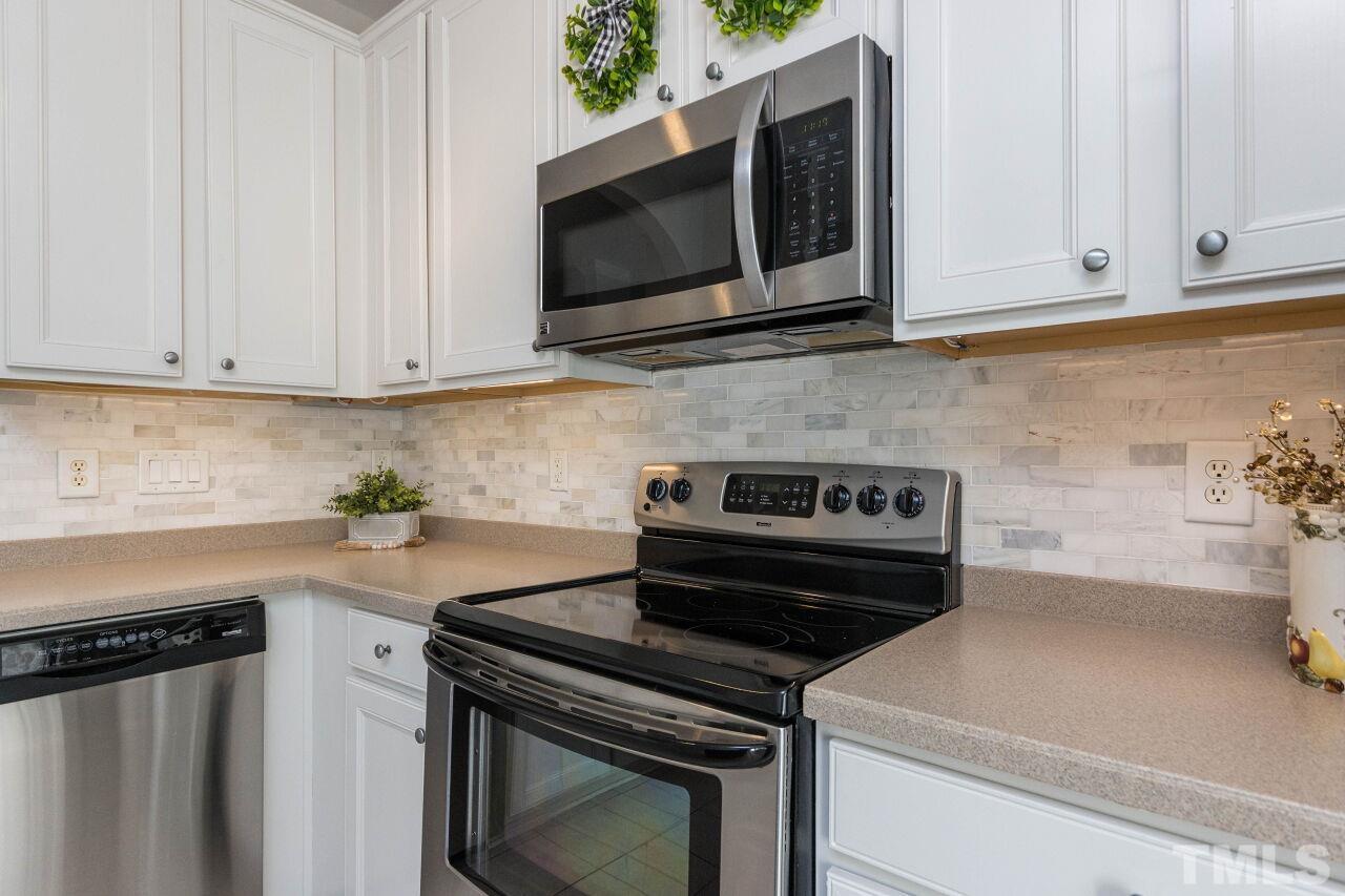 7863 Spungold Street Raleigh, NC 27617 - Photo 10 of 34 a kitchen with stainless steel appliances granite countertop white cabinets and a stove top oven