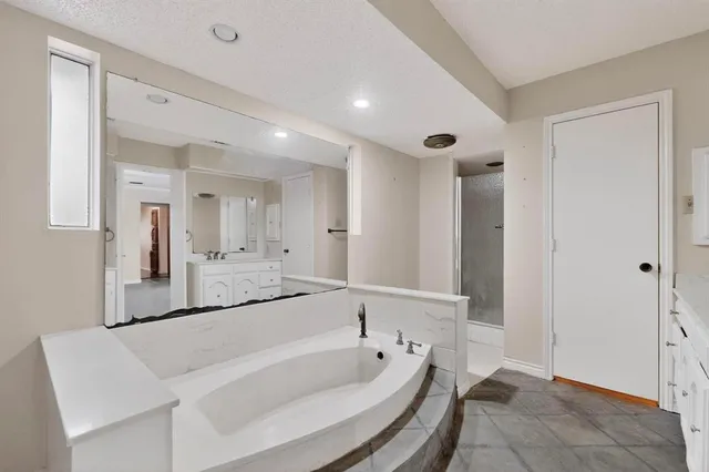 a spacious bathroom with a tub a sink and a mirror