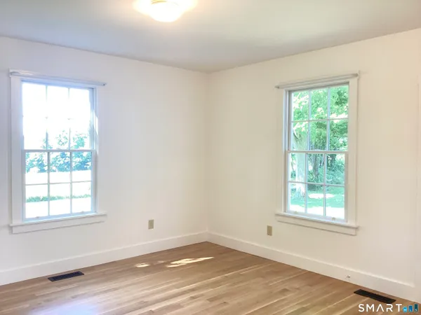 an empty room with wooden floor and window