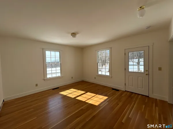an empty room with wooden floor and windows