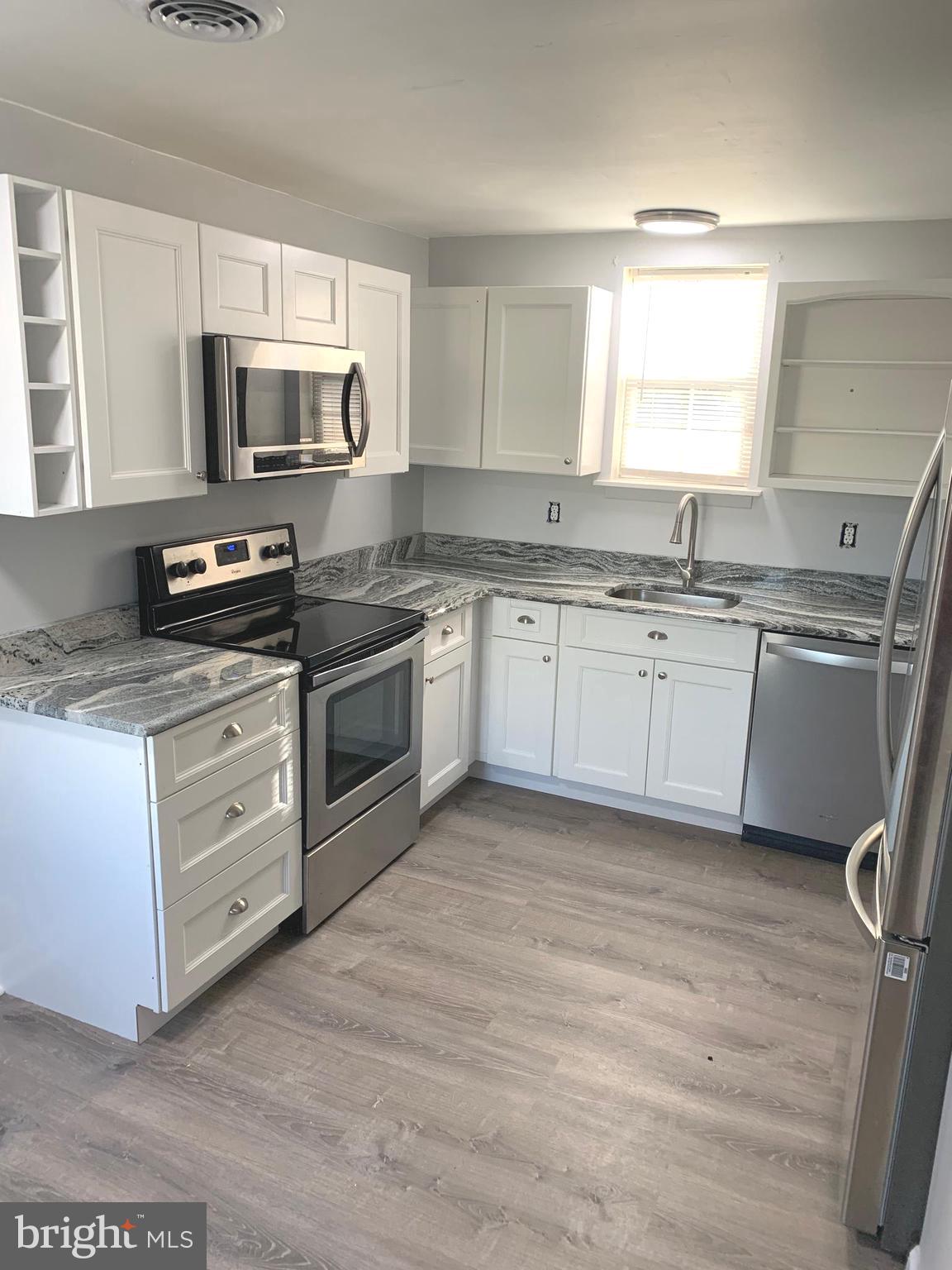 a kitchen with stainless steel appliances granite countertop a stove a sink and a microwave